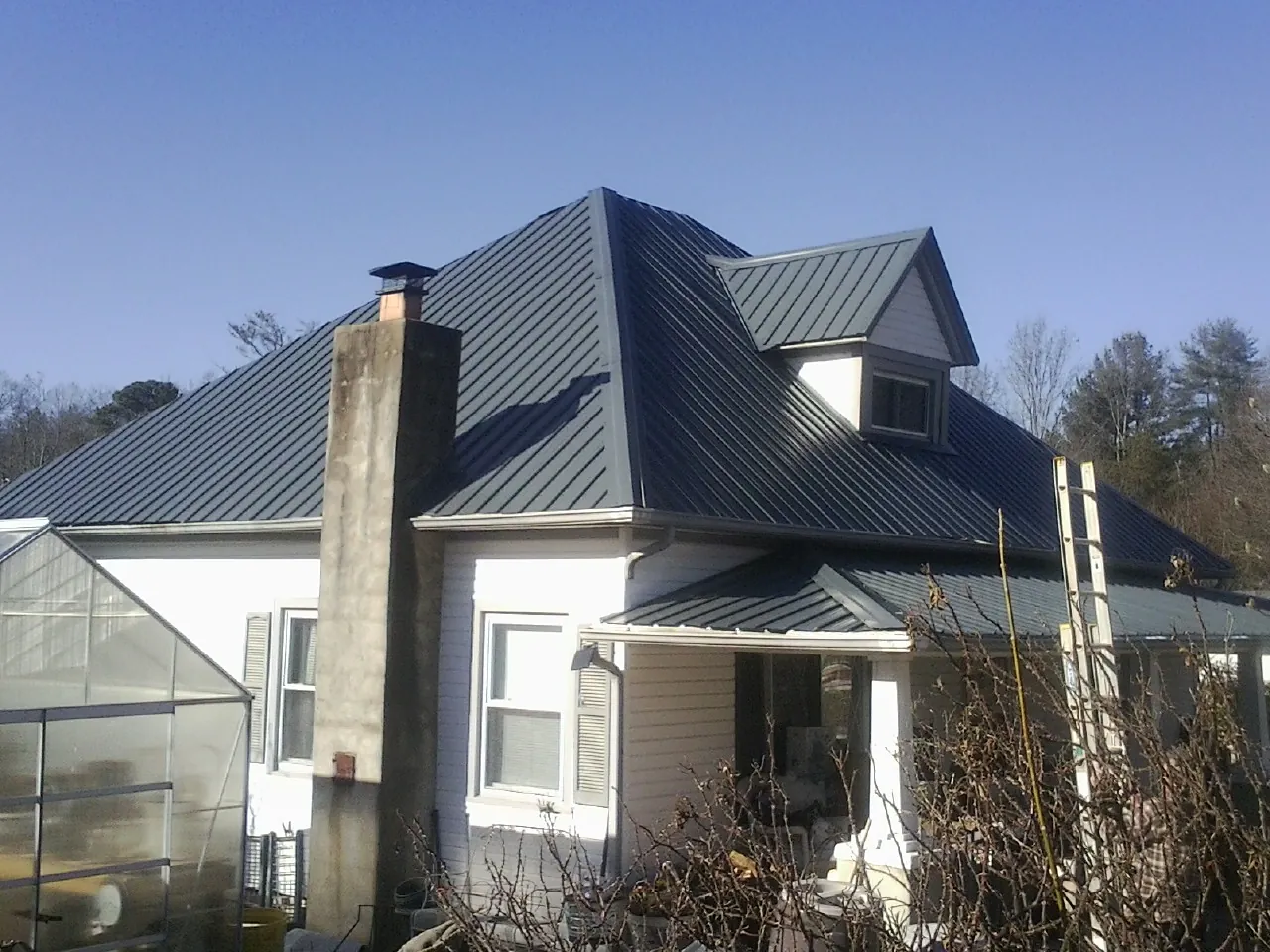 Dark blue standing seam metal roof on a white farmhouse with dormer — Slate & Tile Roof Repair by Roofing Brothers in Michie