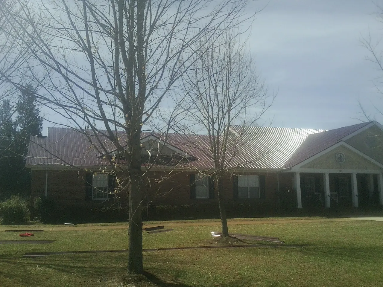 Red metal roof on a brick building seen from the front lawn in Michie