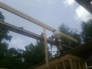 Carpenter setting a ridge beam over a new addition frame — Ice Dam Removal by Roofing Brothers in Michie