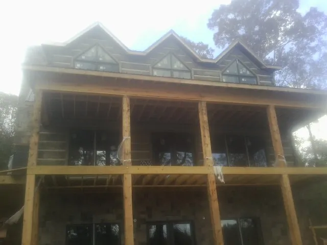 Dormers and porch framing on a large log home under construction — Roof Coating work by our crew in Michie