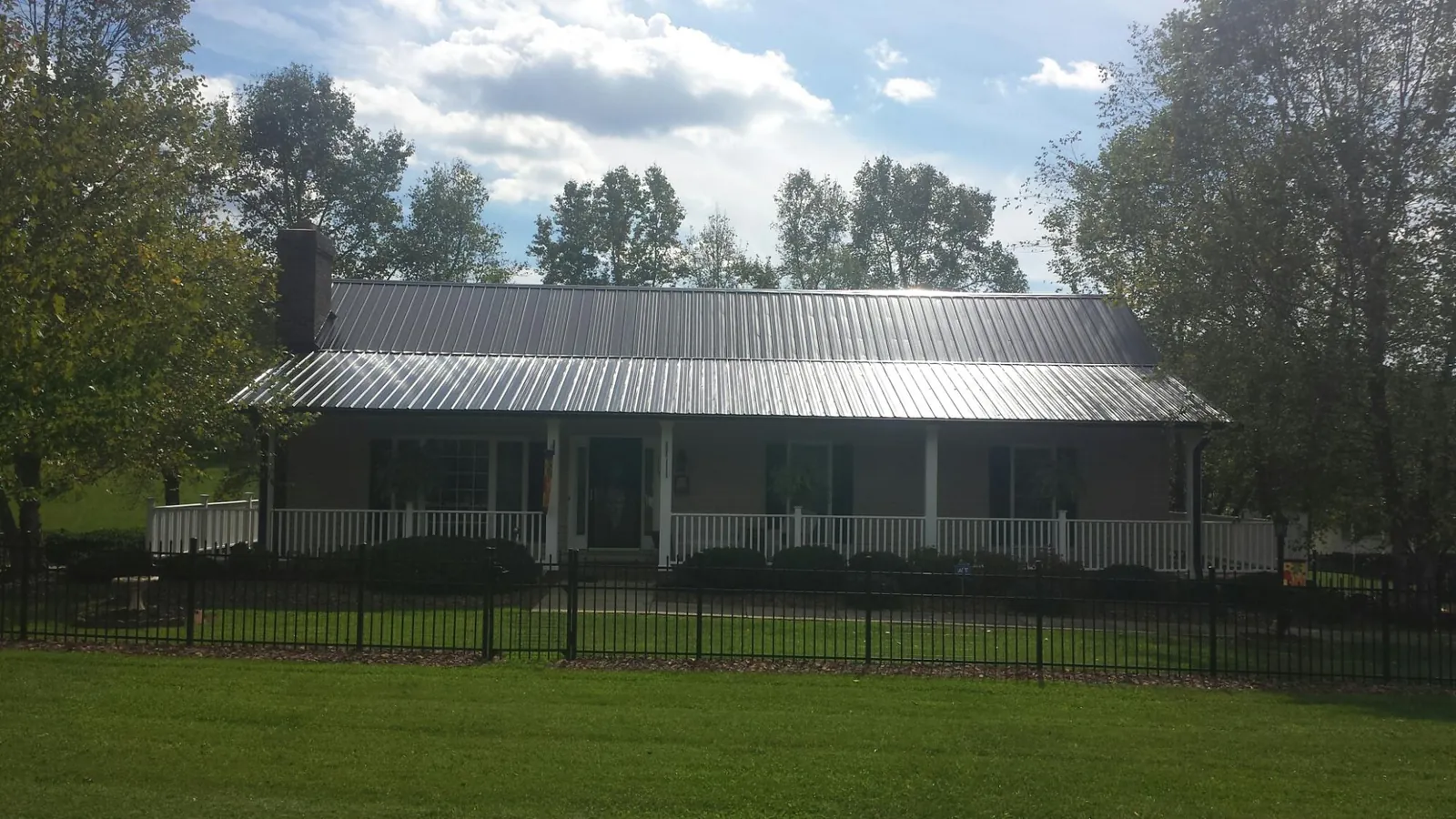 Gray metal roof on a brick ranch with a full width front porch — Gutter Guard Installation work by our crew in Michie