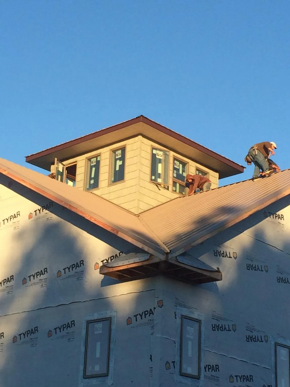 Roofers working around a rooftop cupola on a new metal roof at sunset — Roof Waterproofing in Michie by Roofing Brothers